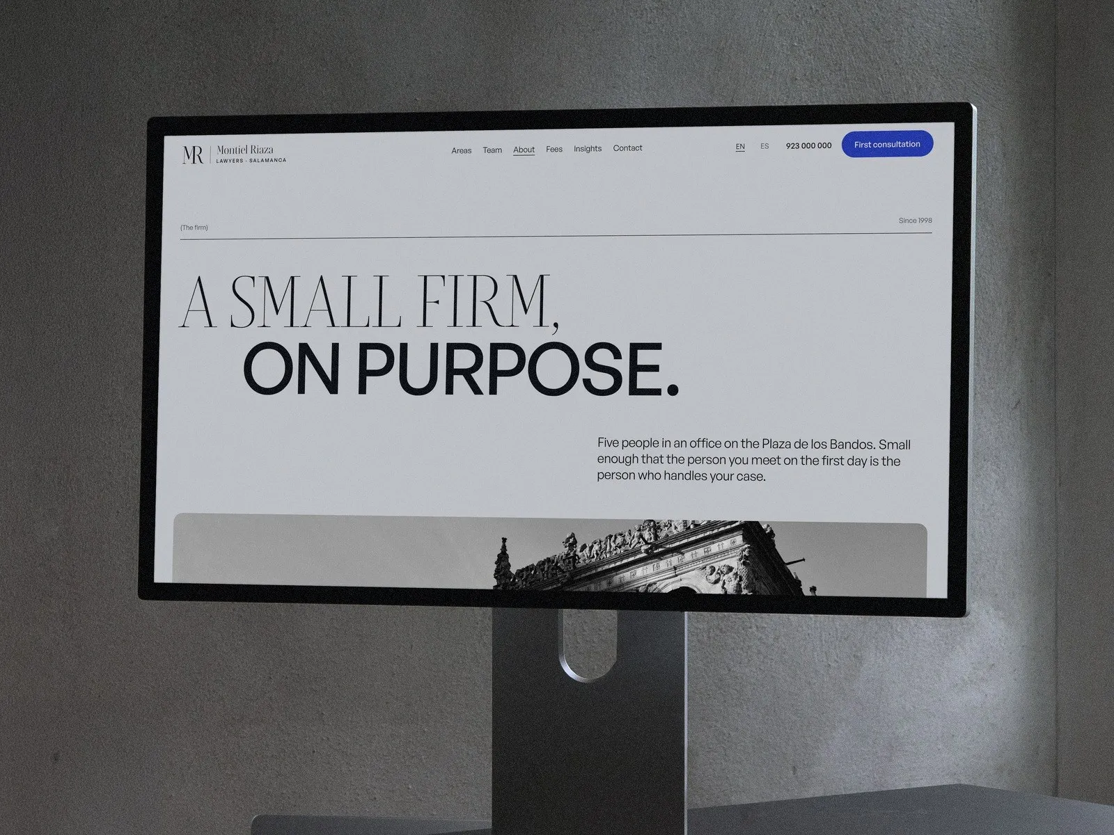 About page «A small firm, on purpose.» on a studio display against a concrete wall